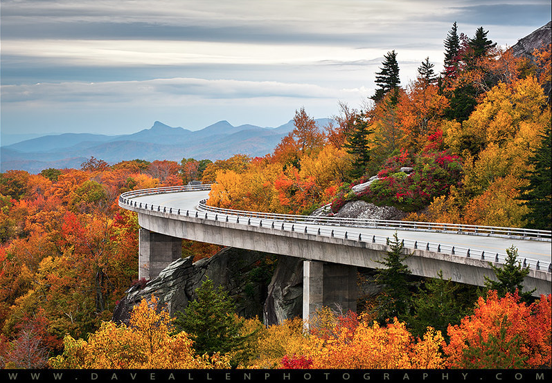 Blue Ridge Parkway viaduct curving through autumn foliage with mountains beyond