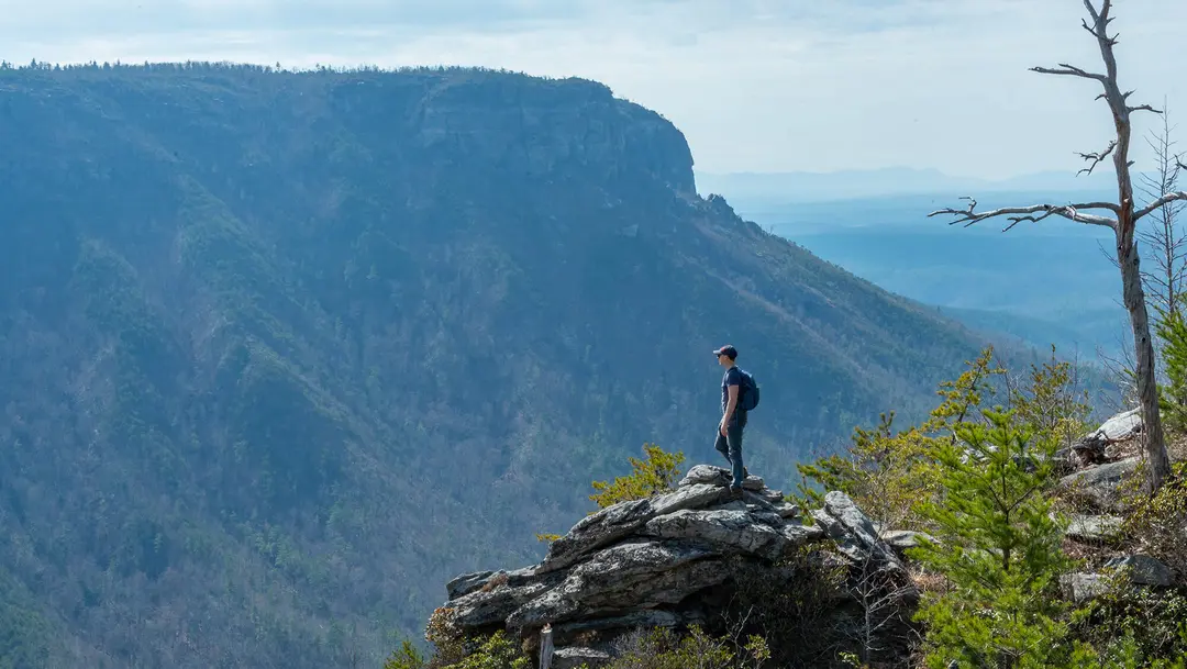 Hiker on a rocky overlook above a forested gorge in the Blue Ridge Mountains